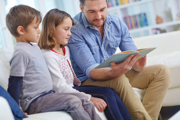 Las historias estimulan las mentes en crecimiento. un padre leyendo una historia a su hijo y su hija en casa - Foto, imagen