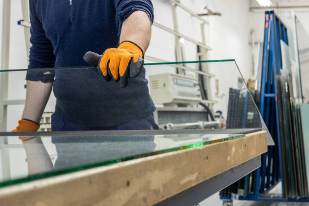 Un vitrier dans une usine de verre enlève un grand morceau de verre d'une table - Photo, image