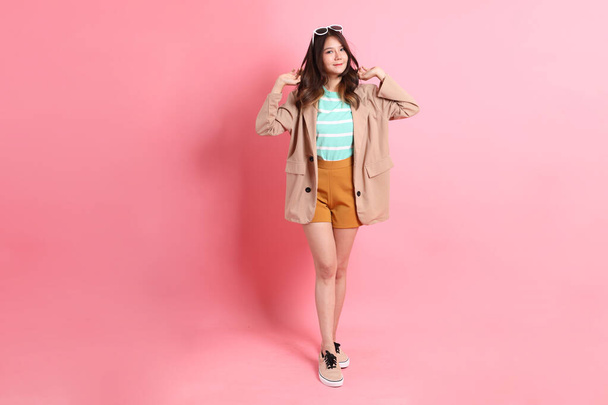 The young adult Asian woman with casual clothes on the pink background. - Photo, image