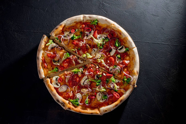 Vegan pizza with tomato sauce, cherry tomatoes, mushrooms, broccoli, red onion on black background. View from above. - Φωτογραφία, εικόνα