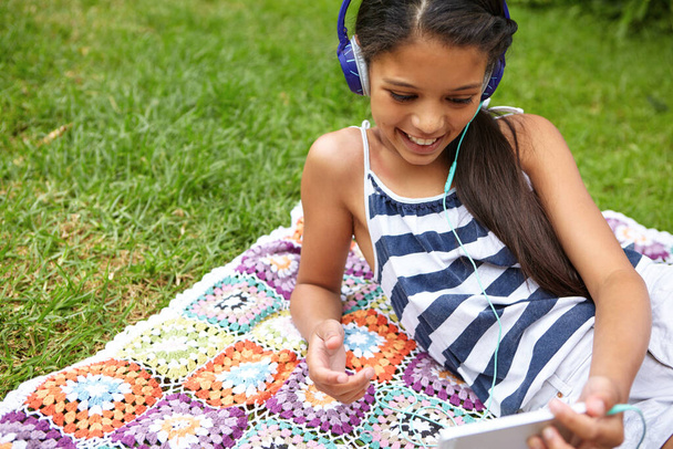 Отдых с великолепными песнями. молодая девушка слушает музыку на своем мобильном телефоне, отдыхая на улице - Фото, изображение