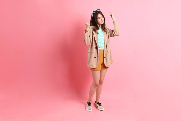 The young adult Asian woman with casual clothes on the pink background. - Zdjęcie, obraz