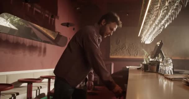 Oldalsó nézet kézi lövés fiatal szakállas férfi csapos vesz alkoholt palack építeni a borhűtő és üzembe bárpultra munka közben - Felvétel, videó