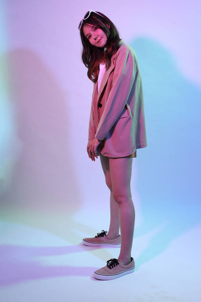 Die junge erwachsene Asiatin in lässiger Kleidung im Neonlicht-Studio. - Foto, Bild