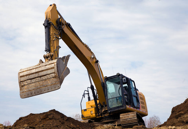 excavator dumping earth backhoe hydraulic shovel digging on construction site heavy equipment earth mover  - Фото, зображення