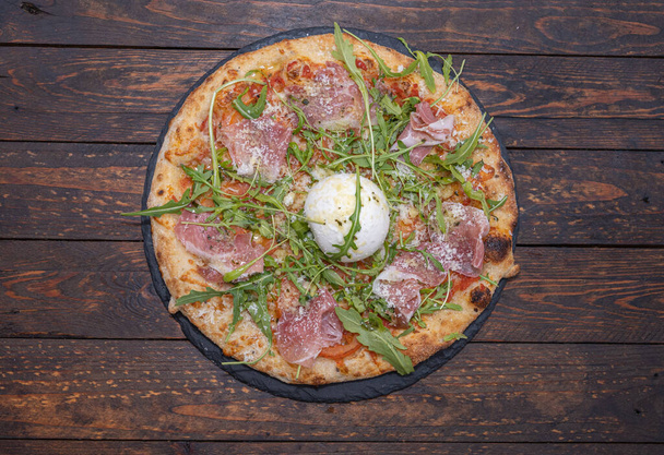 Close-up of pizza with bufalo mozzarella, jamon serrano, rocket salad - Fotó, kép