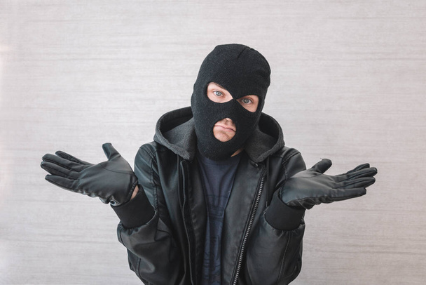 Young handsome man wearing burglar mask clueless and confused with open arms, no idea concept. The thief apologizes. justification for arrest - Fotoğraf, Görsel
