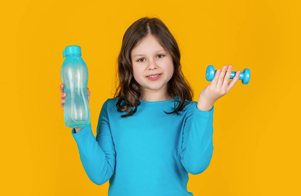 cheerful child with barbell and sport bottle on yellow background. - Foto, Bild