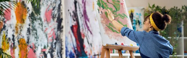 Mujer inspirada, artista femenina en delantal creando pintura abstracta en el taller de estudio en casa. Arte, hobby, concepto de ocio - Foto, imagen