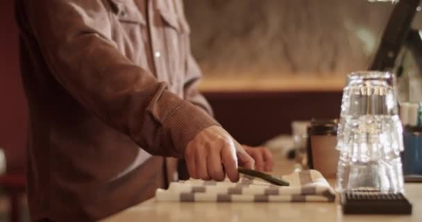Boční pohled ruční záběr mladého vousatého správce mluví přes mobilní telefon s klientem rezervační stůl na večer při práci v moderním vinárně - Záběry, video