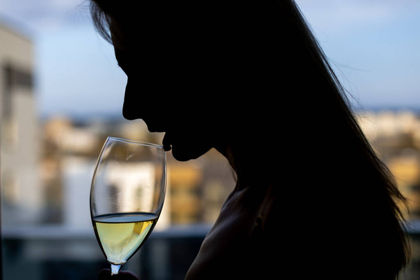 Žena pije bílé víno, silueta se sklem - Fotografie, Obrázek