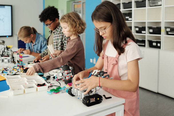 İlköğretim okulunun dört kültürlü öğrencisinin yeni oyuncak robotlar yaparken sınıfın detaylarıyla birlikte masada durması. - Fotoğraf, Görsel