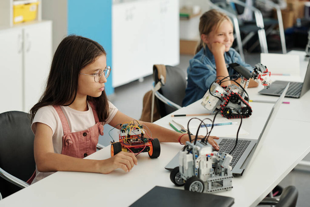 Akıllı öğrenci elektronik dokümana bilgi giriyor ve oyuncak robotu tanımlarken dizüstü bilgisayar ekranına bakıyor. - Fotoğraf, Görsel