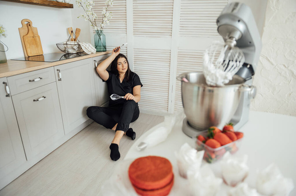 Woman cook sits on the floor against the background of a blender. Tired of a lot of orders - Foto, Imagem