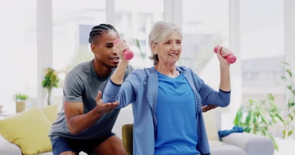 Rehabilitation, strong and woman with a physiotherapist for exercise, strength training and support. Help, fitness and a senior patient lifting dumbbells with black man in physiotherapy for recovery. - Footage, Video