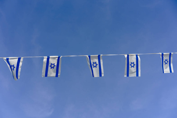 Flaga Izraela trzepotanie na tle błękitnego nieba z białymi chmurami w Dniu Niepodległości Izraela. - Zdjęcie, obraz