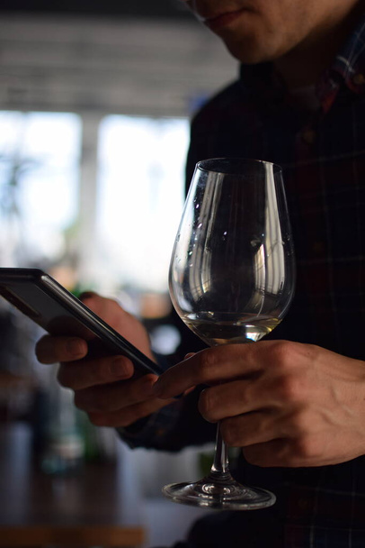  Man with glass of white wine looking at phone - Foto, Imagen