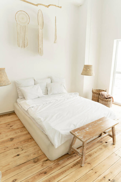 a beautiful bright room with a large bed and a white bed. eco style interior. wooden floor. beautiful decor - Фото, изображение