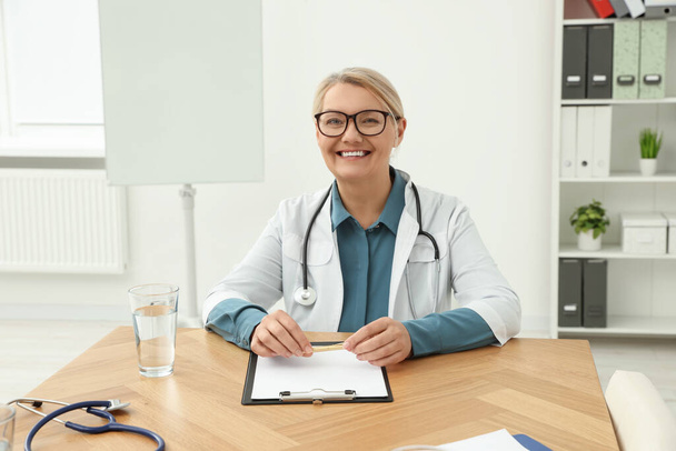 Professional doctor sitting at wooden table in clinic - Photo, Image