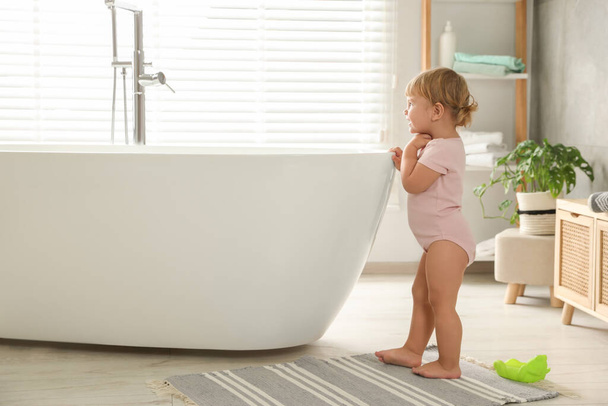 Симпатична маленька дівчинка біля ванни у ванній
 - Фото, зображення