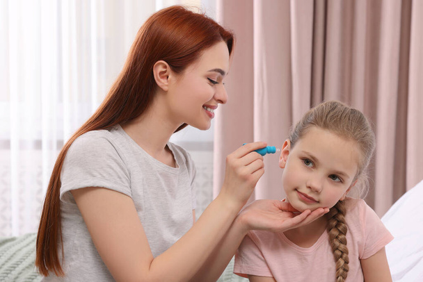 Mother dripping medication into daughter's ear at home - Valokuva, kuva