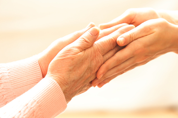 Old and young holding hands on light background, closeup - Photo, Image