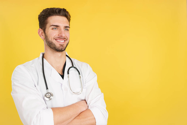 Ystävällinen valkoihoinen lääkäri univormussa ja stetoskooppi studiossa keltaisella taustalla - Valokuva, kuva