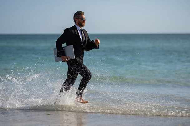 Excited businessman in wet suit run in sea. Funny business man, crazy comic business concept. Remote online working. Crazy summer business. Fun business lifestyle. Funny freelance businessman - Фото, изображение