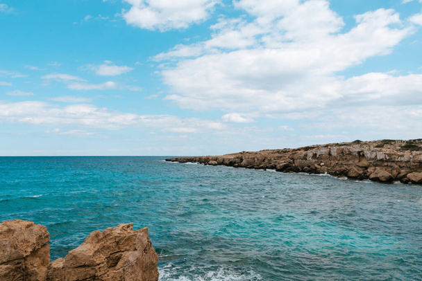 Widok pięknej niebieskiej laguny między skałami z błękitnym niebem w tle. Widok na morze z turkusową wodą w słoneczny dzień. - Zdjęcie, obraz