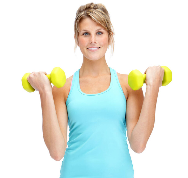 Working towards her best health. Attractive young woman in sportswear lifting dumbbells while isolated on white - Foto, afbeelding