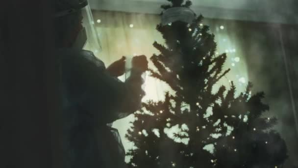 Close-up van de droevige arts in beschermend pak en vizier siert de kerstboom met medische maskers. Dan scheurt de maskers af en ontspoort met ornamenten. Kerstmis en het nieuwe jaar vieren - Video