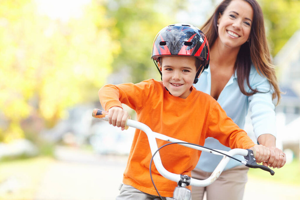 Annem düşmesine izin vermez. Genç bir anne oğluna bisiklet sürmeyi öğretiyor. - Fotoğraf, Görsel