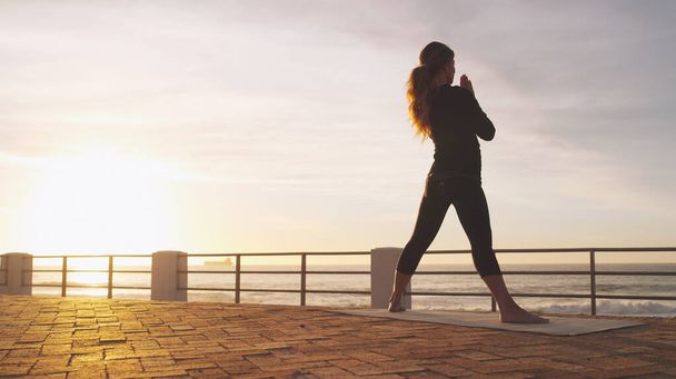 Prowadź spokojne życie. kobieta ćwicząca jogę na promenadzie - Zdjęcie, obraz