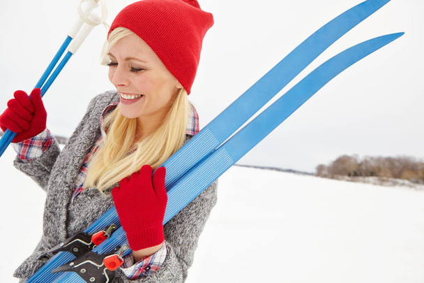 Heading to the slopes for some exercise. a young woman holding ski equipment - Фото, изображение