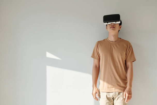 Νεαρός άνδρας παίζει παιχνίδι σε γυαλιά εικονικής πραγματικότητας στο σπίτι - Φωτογραφία, εικόνα