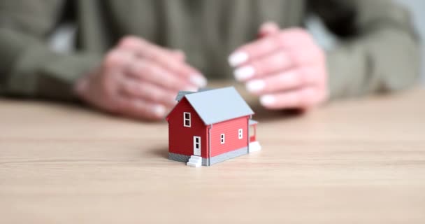 Las manos cierran el modelo de la casa roja en la mesa, de cerca. Concepto de seguridad de la vivienda, alarma - Metraje, vídeo
