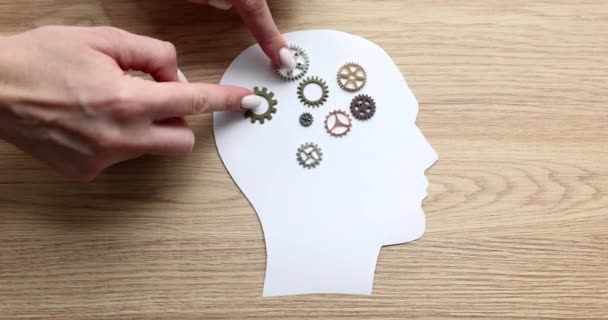 Hands move gears on a paper model of the head, a close-up. Cognitive functions, brainstorming slowmotion - Footage, Video