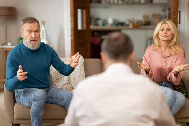 Unzufriedene Ehepartner mit Ehetherapie beschweren sich bei einem professionellen Psychologen, der Konflikte auf der Couch im Haus hat. Ehepartner streiten sich bei Psychotherapie-Termin Selektiver Fokus - Foto, Bild