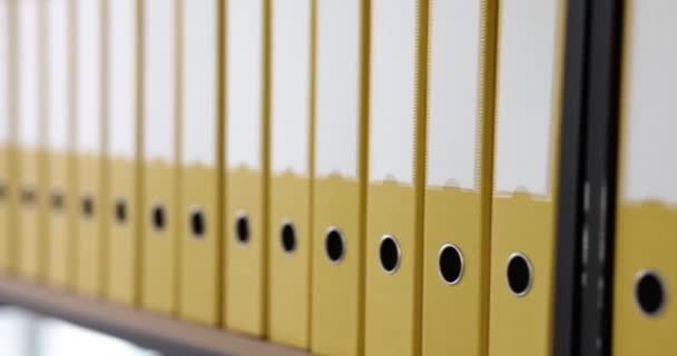 Carpetas amarillas en fila en el rack, de cerca. Optimización del almacenamiento de documentos en la oficina - Imágenes, Vídeo