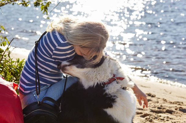 Owner with a siberian laika dog on a beach. Friendship of a dog and a woman - Photo, image