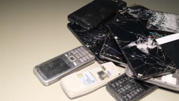 Egy halom elromlott telefon, törött kijelzővel. Hibás, hibás és elavult felszerelés, régi telefonok. 4k videó - Felvétel, videó