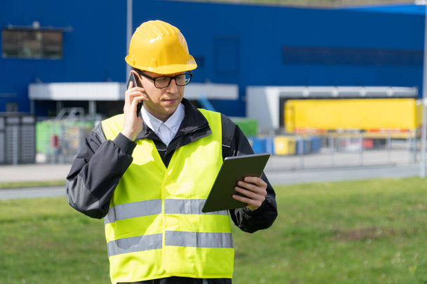 Logistician with phone and digital tablet on a background of logistic center. High quality photo - Фото, зображення