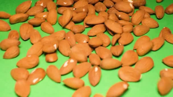 Mantelipähkinät putoavat vihreälle pohjalle. Mantelit ovat runsaasti vitamiineja A ja E, jotka ovat tärkeitä suojaamaan immuunijärjestelmää - Materiaali, video