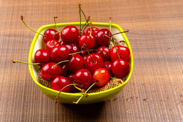 cerezas rojas maduras frescas en un tazón sobre fondo de madera - Foto, Imagen