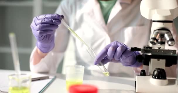 研究室のアシスタントは、ピペット、クローズアップとフラスコに黄色の液体を注ぎます。実験室試験、診断 - 映像、動画