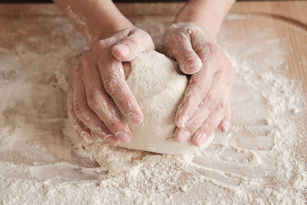 Close-up of unrecognizable woman touching dough ball on board with flour while kneading - Foto, Imagem