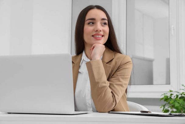 Young female intern working with laptop at table in office - Foto, Bild