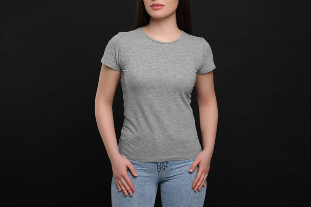 Woman wearing grey t-shirt on black background, closeup - Zdjęcie, obraz