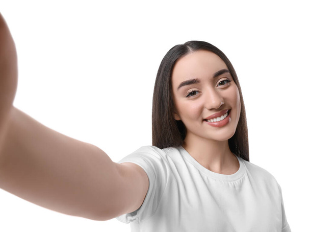 Усміхнена молода жінка бере селфі на білому тлі
 - Фото, зображення