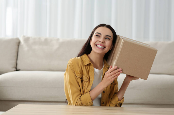 Happy young woman with parcel at home. Internet shopping - Fotoğraf, Görsel